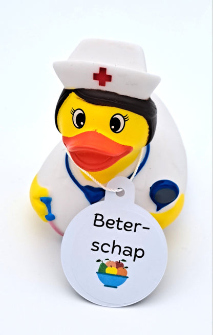Gele verpleegsterbadeend met wit uniform, witte kap met rood kruis, blauwe stethoscoop en een witte hangtag met de tekst ‘Beterschap’.