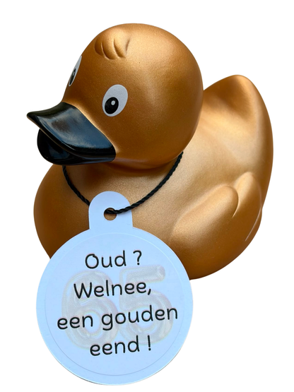 Goudkleurige badeend met zwarte snavel en een hangtag met het getal 65 en de tekst ‘Oud? Welnee, een gouden eend!’.