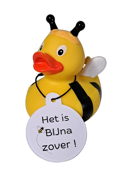 Gele bijenbadeend met zwarte strepen en voelsprieten, witte vleugels en een witte hangtag met de tekst ‘Het is BIJna zover!’ en een bijtje.