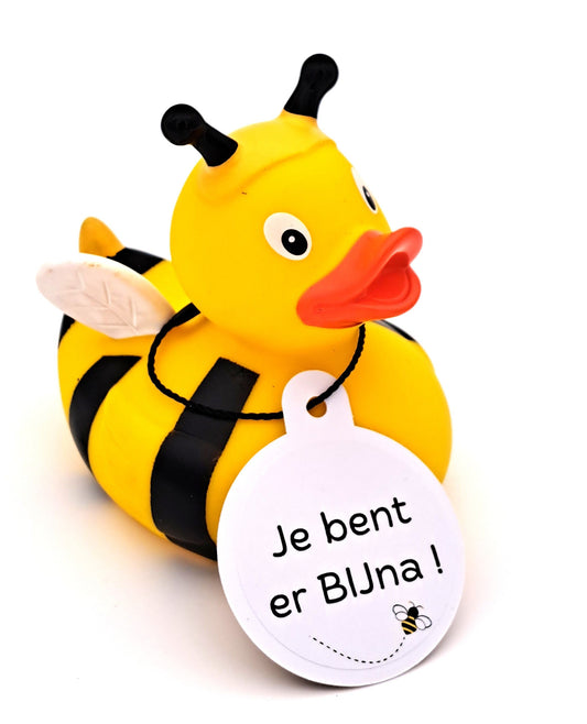 Gele bijenbadeend met zwarte strepen en voelsprieten, witte vleugels en een witte hangtag met de tekst ‘Je bent er BIJna!’ en een bijtje.