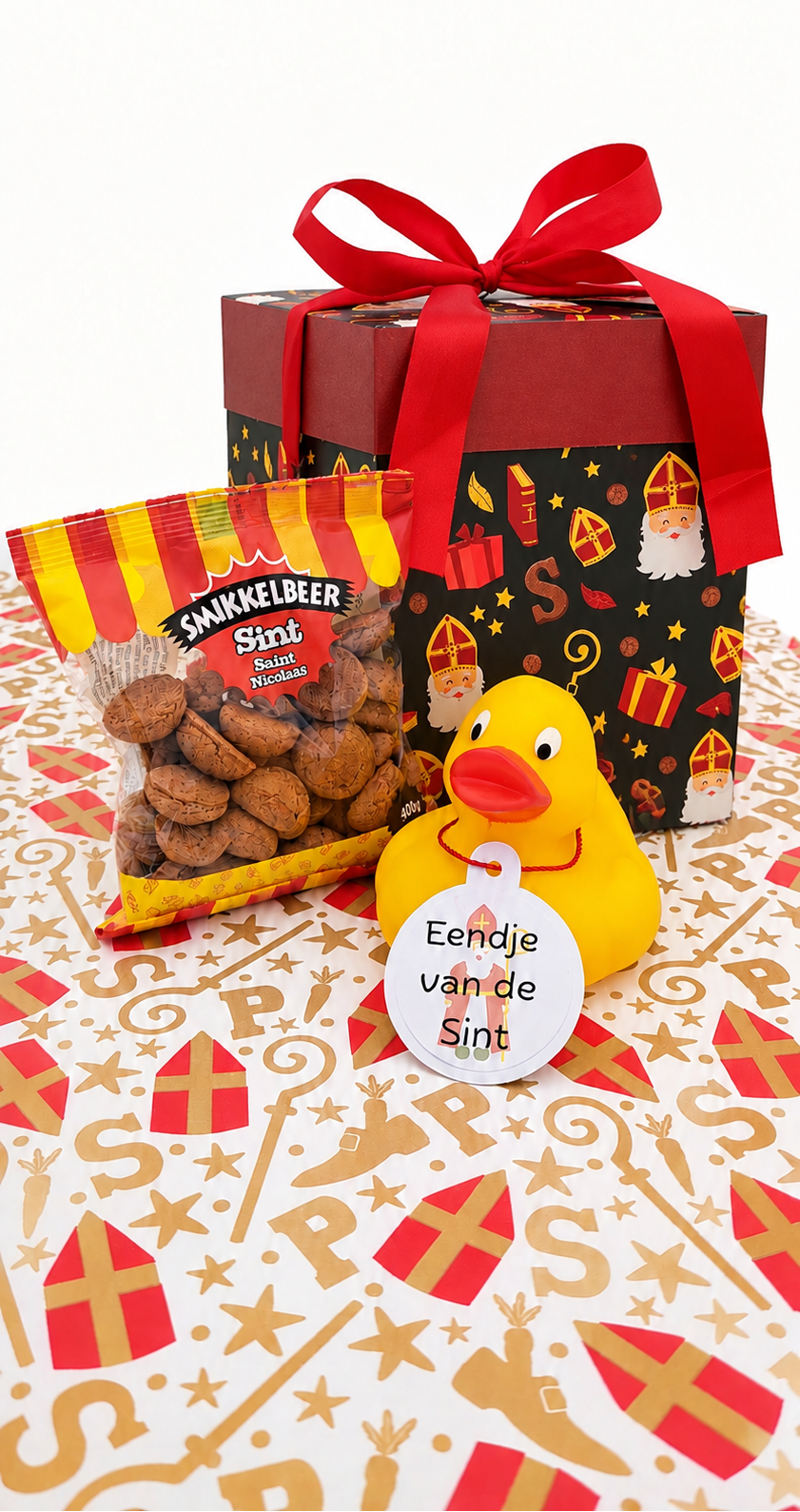 Gele badeend met hangtag ‘Eendje van de Sint’, naast een zak kruidnoten en een Sinterklaascadeaudoos met rode strik op feestelijk inpakpapier.