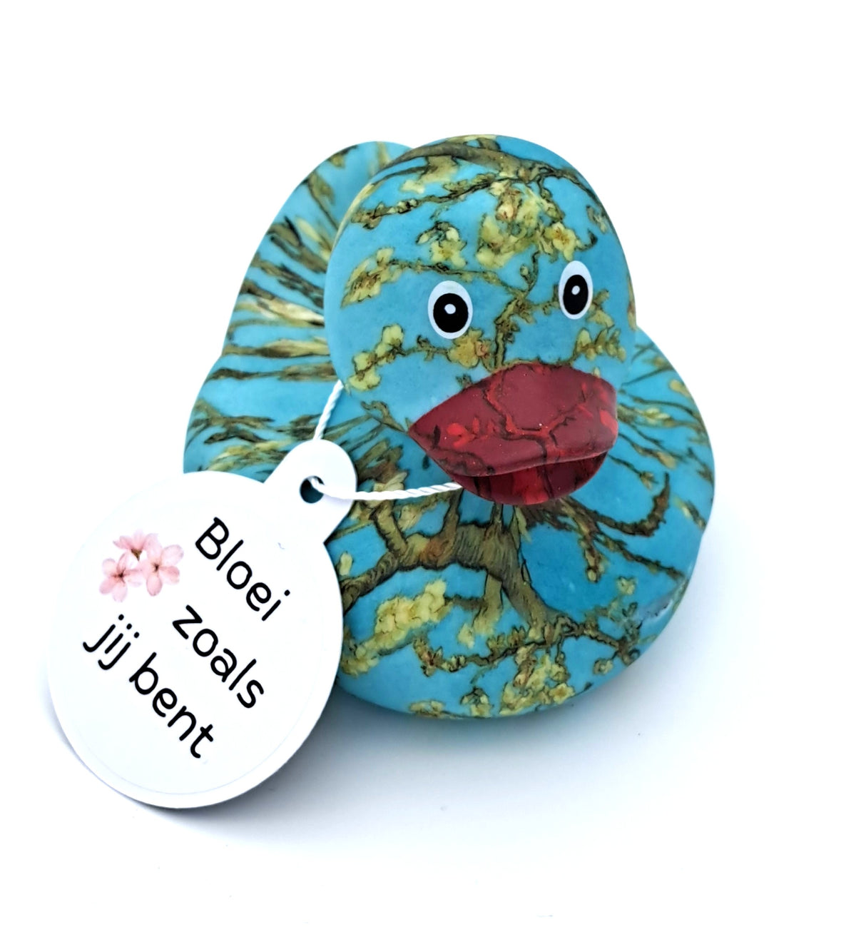 Blauwe badeend met Van Goghs Amandelbloesem als patroon, donkerrode snavel en een witte hangtag met de tekst ‘Bloei zoals jij bent’.