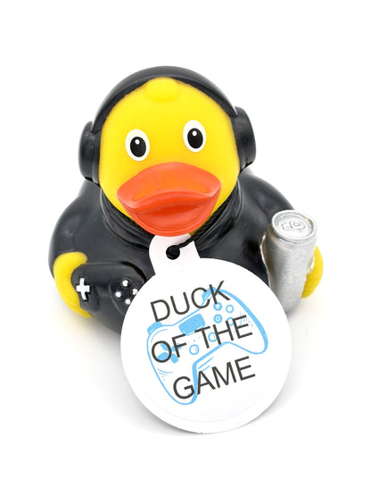 Gele gamerbadeend met zwarte koptelefoon en kleding, een gamecontroller, een zilverkleurig blikje en een witte hangtag met de tekst ‘DUCK OF THE GAME’.